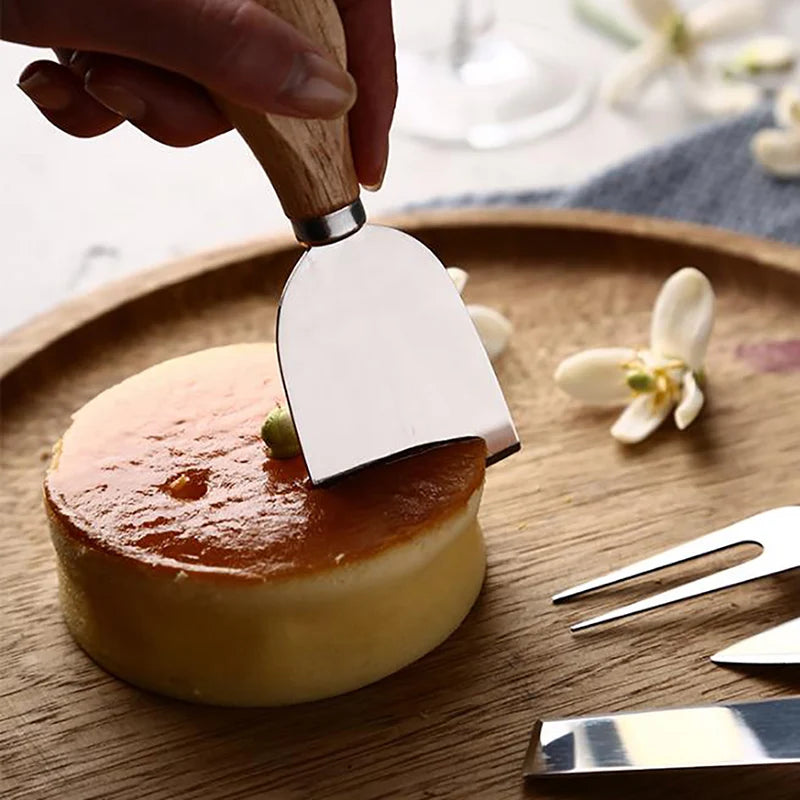 Person using a spatula to cut into a small round cake on a wooden plate.