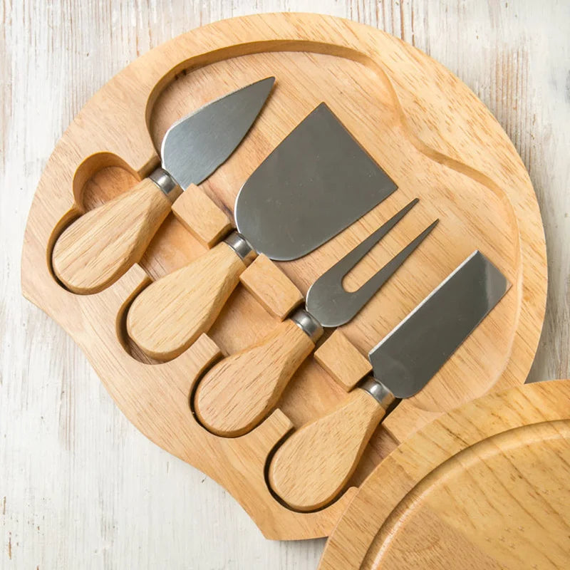 Wooden cheese board set with metal tools on a light wooden surface