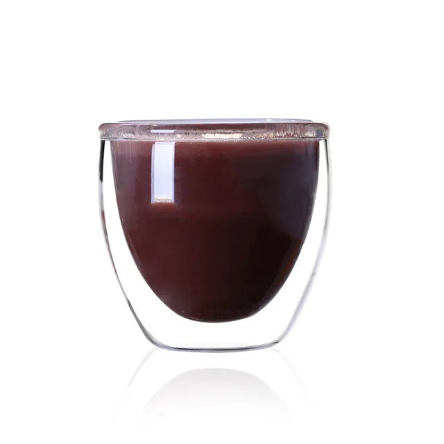 Clear glass cup with dark liquid on a white background