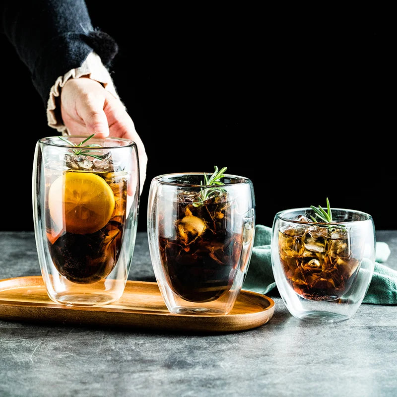 Three glass cups with iced beverages on a wooden tray against a dark background