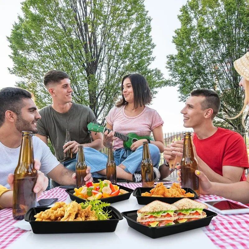 Group of friends enjoying a meal outdoors with food and drinks on a table.
