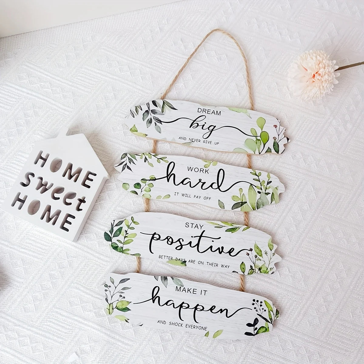 Decorative wooden signs with motivational phrases and floral designs on a white textured surface.