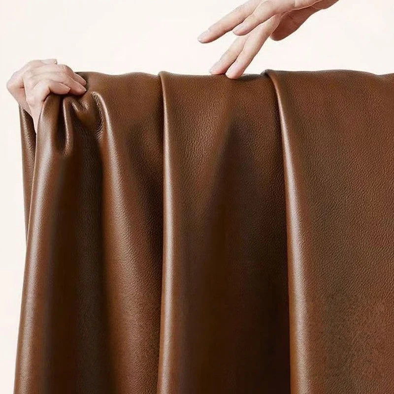 Brown leather fabric with hands holding it on a light beige background