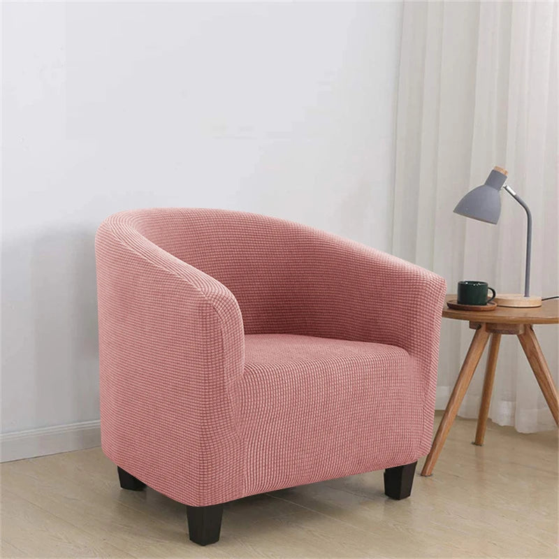 Pink armchair in a room with a side table and lamp.