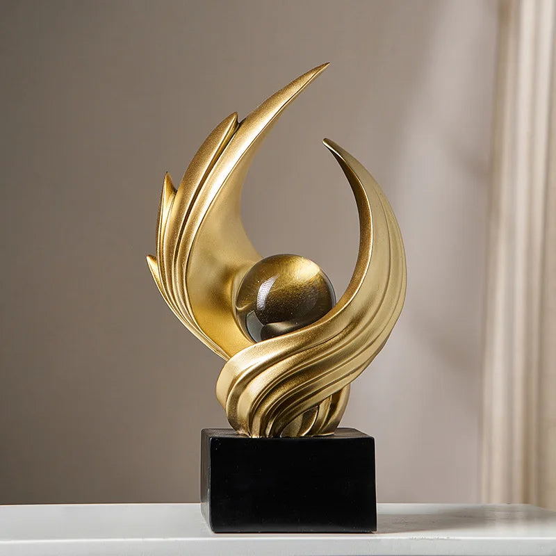 Gold abstract sculpture on a black base against a neutral background