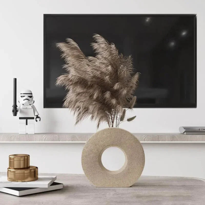 Modern living room with a flat-screen TV, decorative plant, and small sculptures.