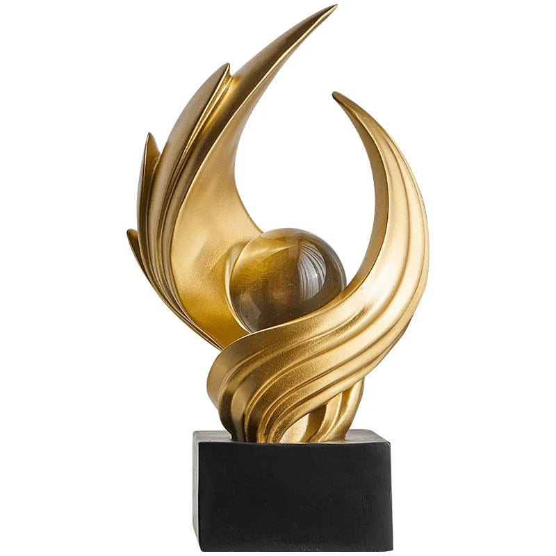 Gold abstract sculpture on a black base against a white background