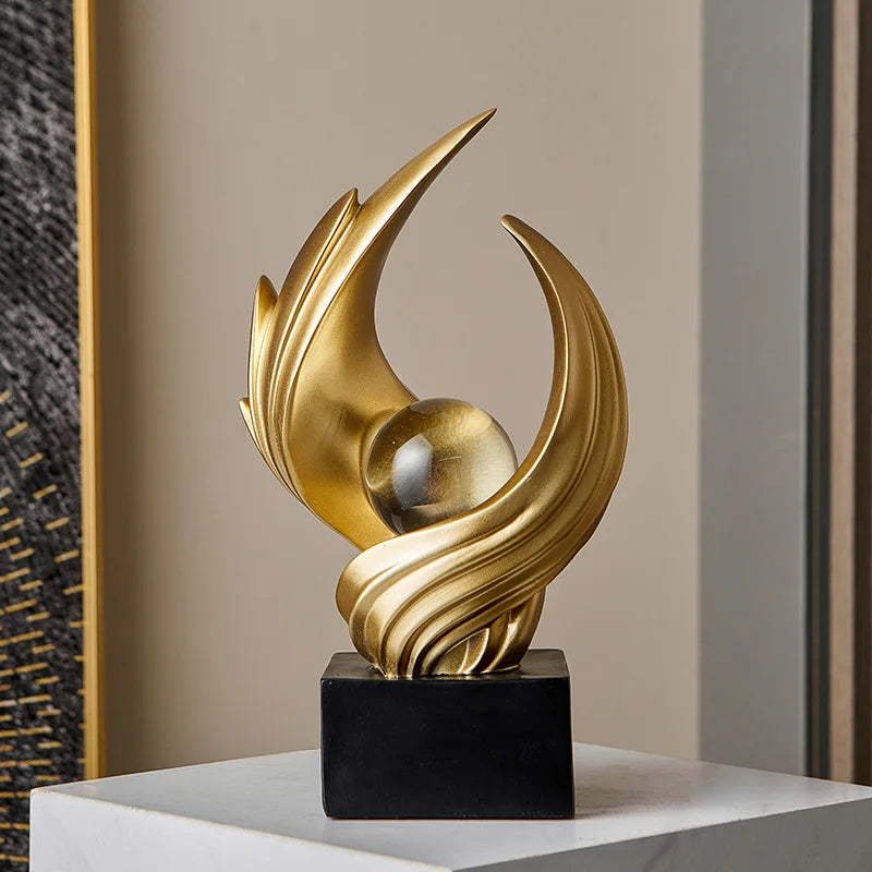 Gold abstract sculpture on a black base against a neutral wall