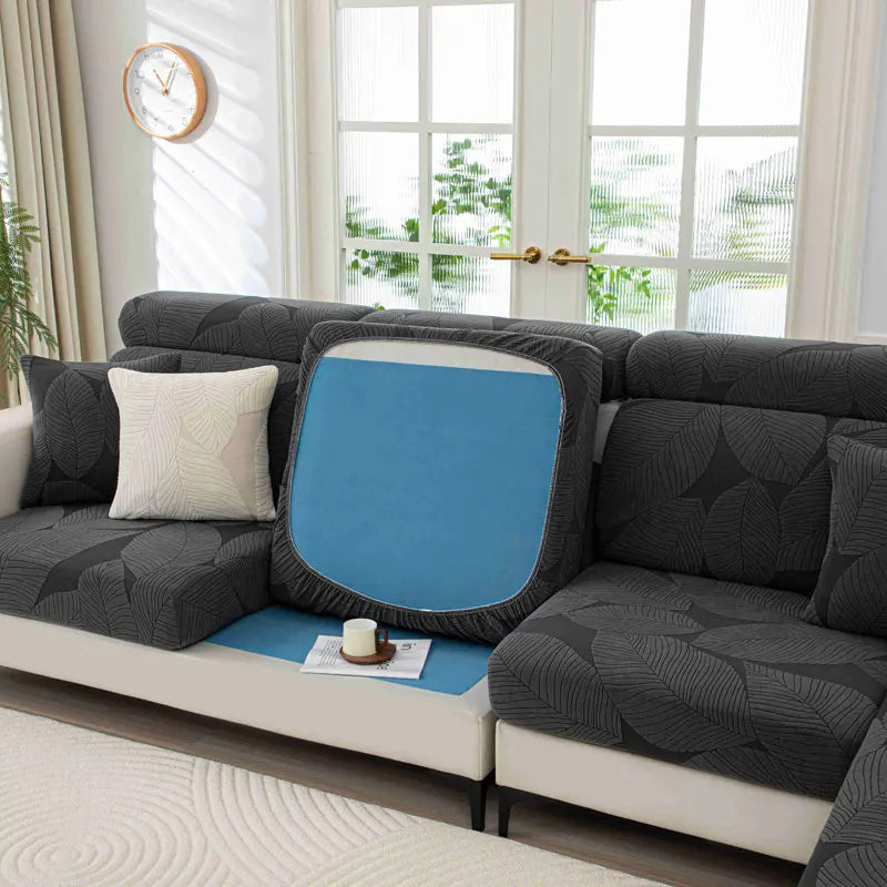 Gray sectional sofa with a blue cushion on a white rug in a bright room.