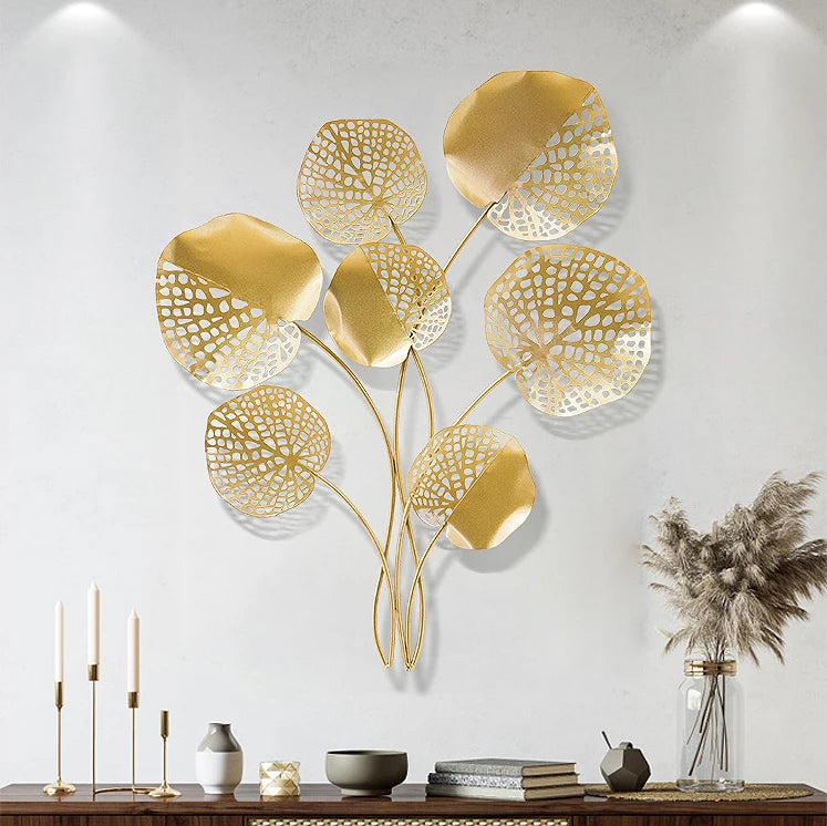 Gold leaf wall art on a white wall with decorative items below.