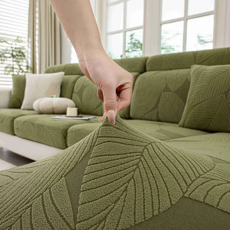 Green textured fabric being draped over a sofa with leaf pattern