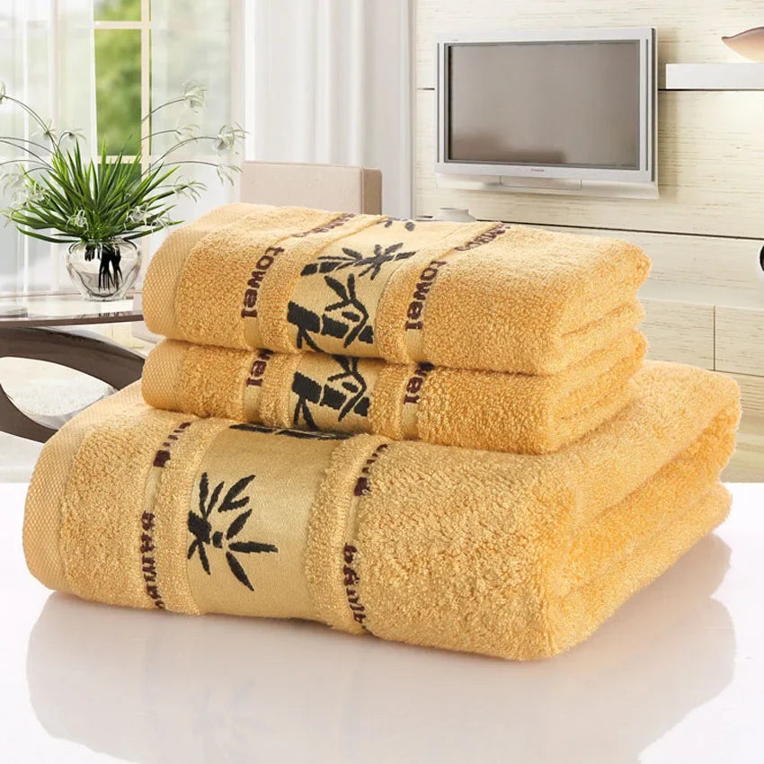 Set of yellow towels with black text and bamboo design on a reflective surface.