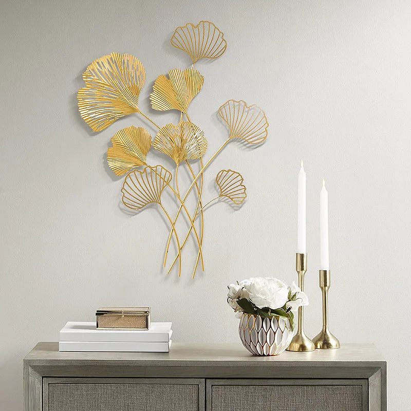 Decorative gold leaf wall art above a wooden console table with candles and a vase.