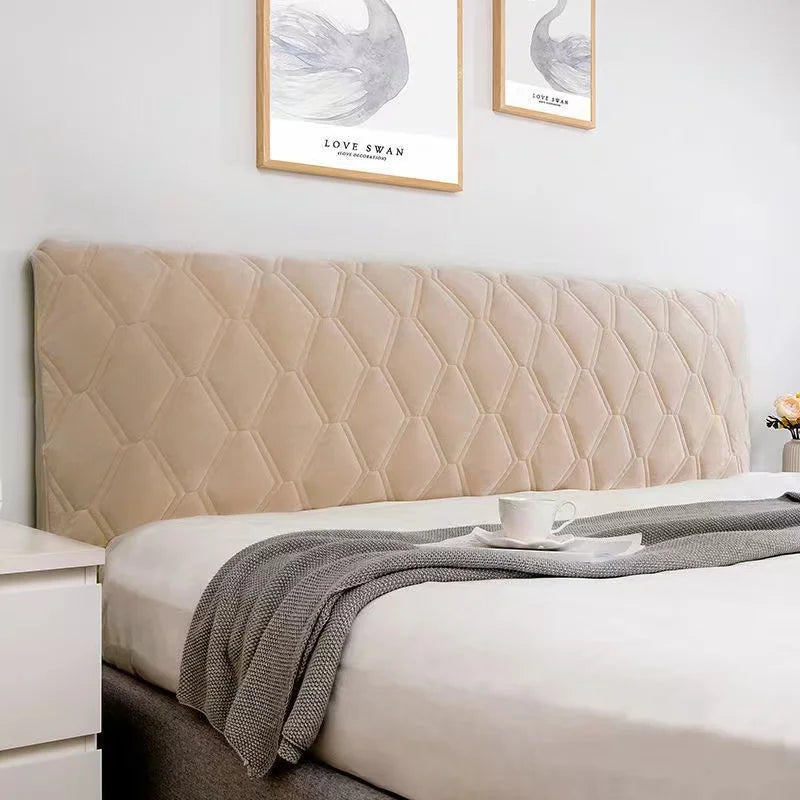 Beige quilted headboard on a bed with white bedding and gray blanket, framed artwork on the wall.