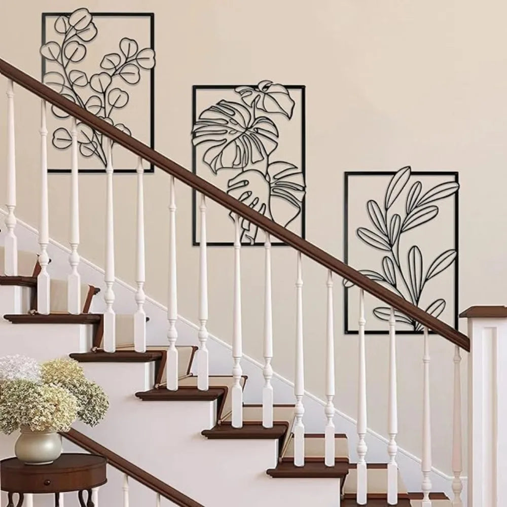 Staircase with wooden handrail and white balusters, featuring decorative leaf wall art.
