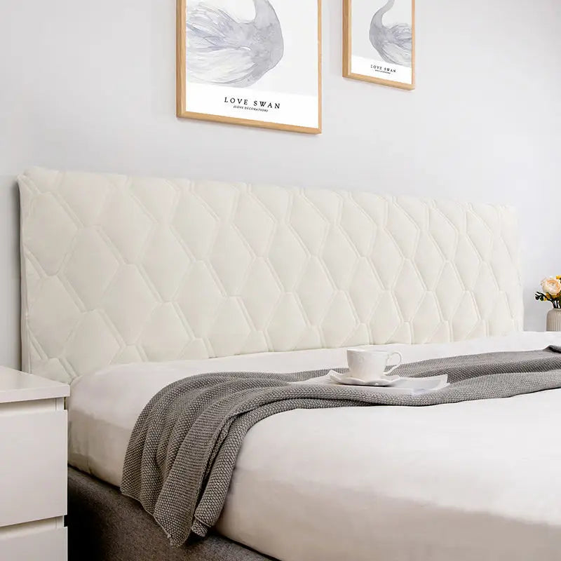Bedroom with a bed featuring a textured headboard and gray blanket, with two framed artworks on the wall.