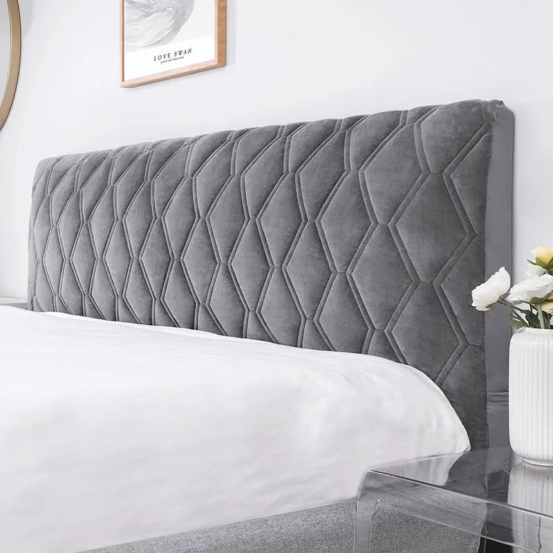 Gray quilted headboard on a bed with a white comforter in a bedroom setting.