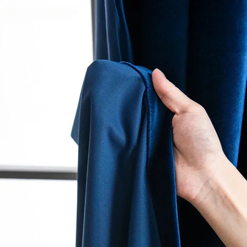 Hand adjusting a blue curtain panel against a neutral background