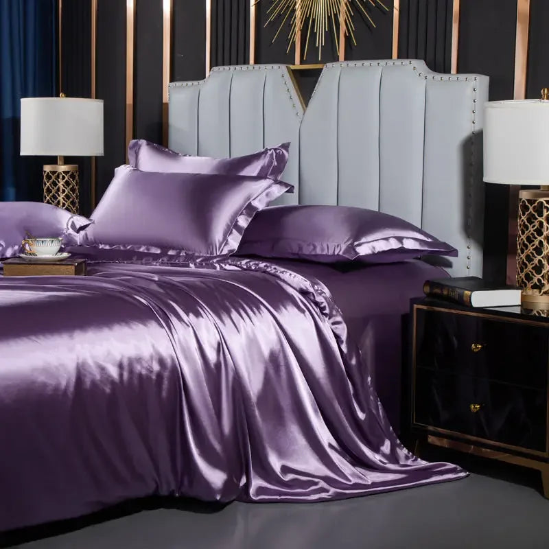 Purple satin bedding set on a bed with matching pillows and a decorative headboard.