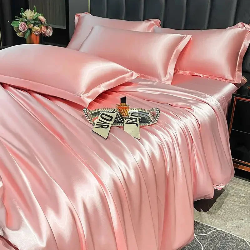 Pink satin bedding set on a bed with a decorative tray and flowers in the background.