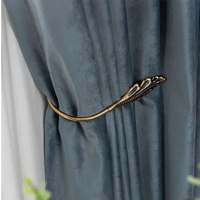 Gold curtain tieback with decorative design on a blue curtain