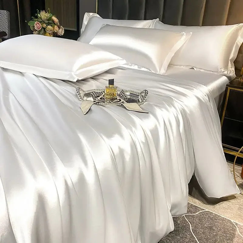 Silky white bedding set on a bed with decorative items.