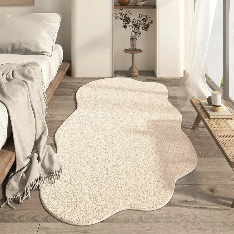 Beige rug on a wooden floor in a room with a bed and small table.