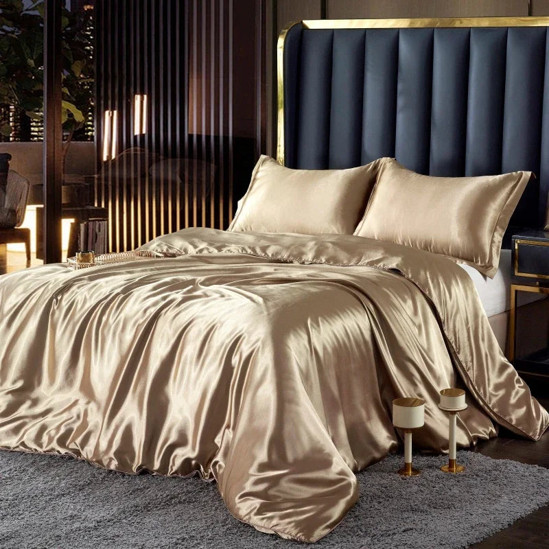 Beige satin bedding set on a bed with a dark blue upholstered headboard.