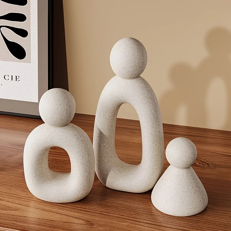 Three stone-like sculptures on a wooden surface with a neutral background