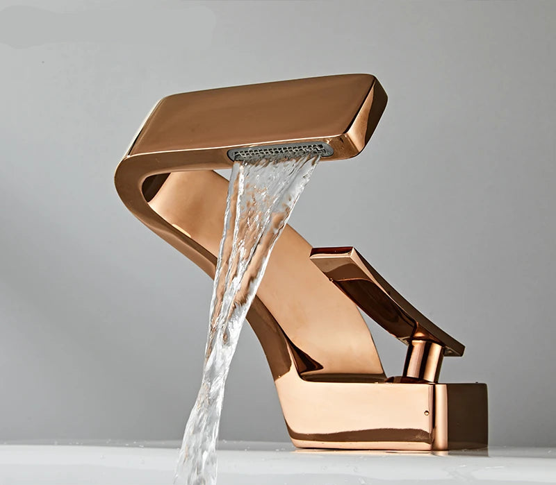Rose gold waterfall hot & cold water faucet with water flowing, brand 'TOLM' visible.