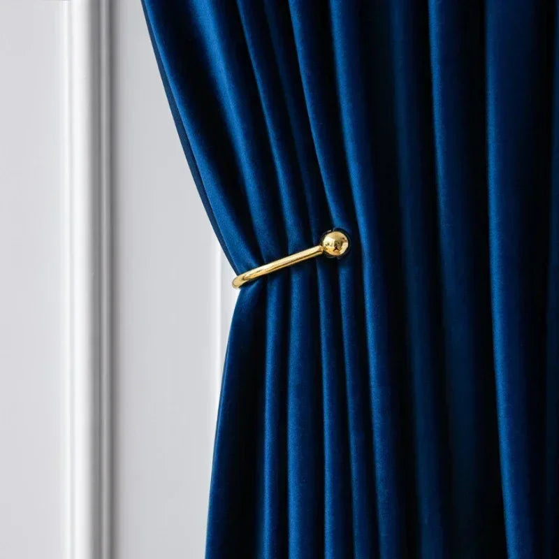 Blue curtain with a gold tie-back against a white wall