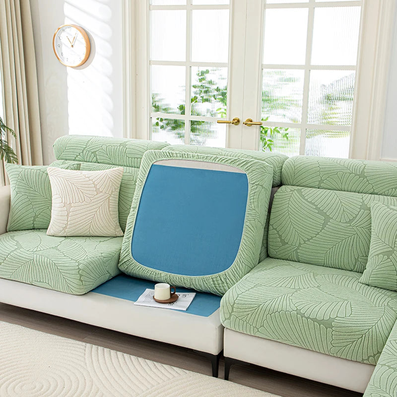 Green sofa with a blue cushion in a bright room with large windows.