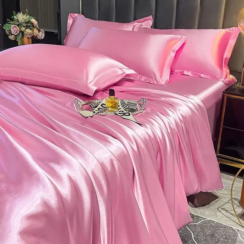 Pink satin bedding set on a bed with a decorative tray and flowers.