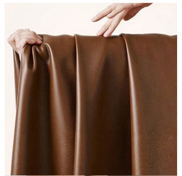 Brown leather fabric with hands stretching it on a light background