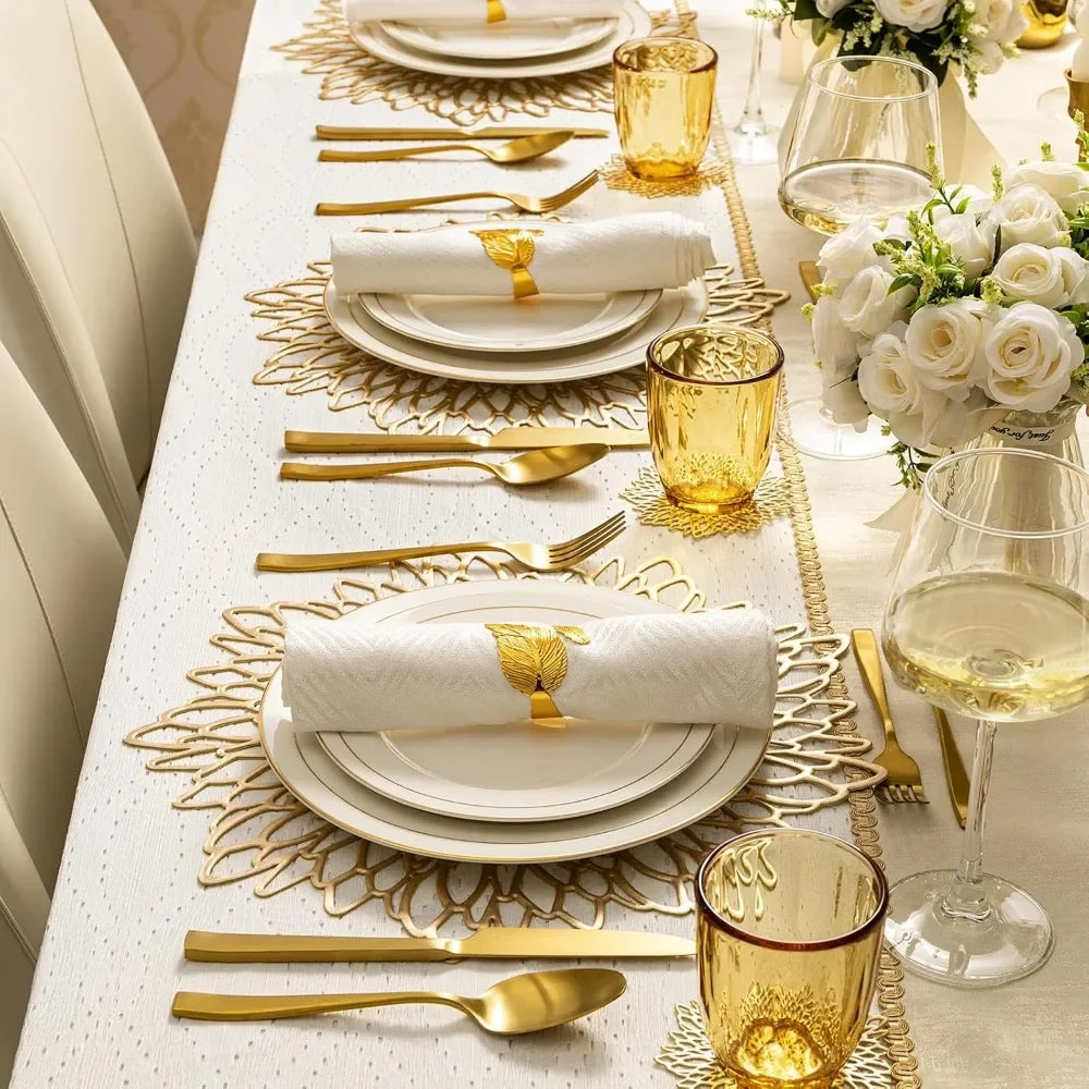 Elegant dining table setting with gold cutlery, glasses, and white plates.
