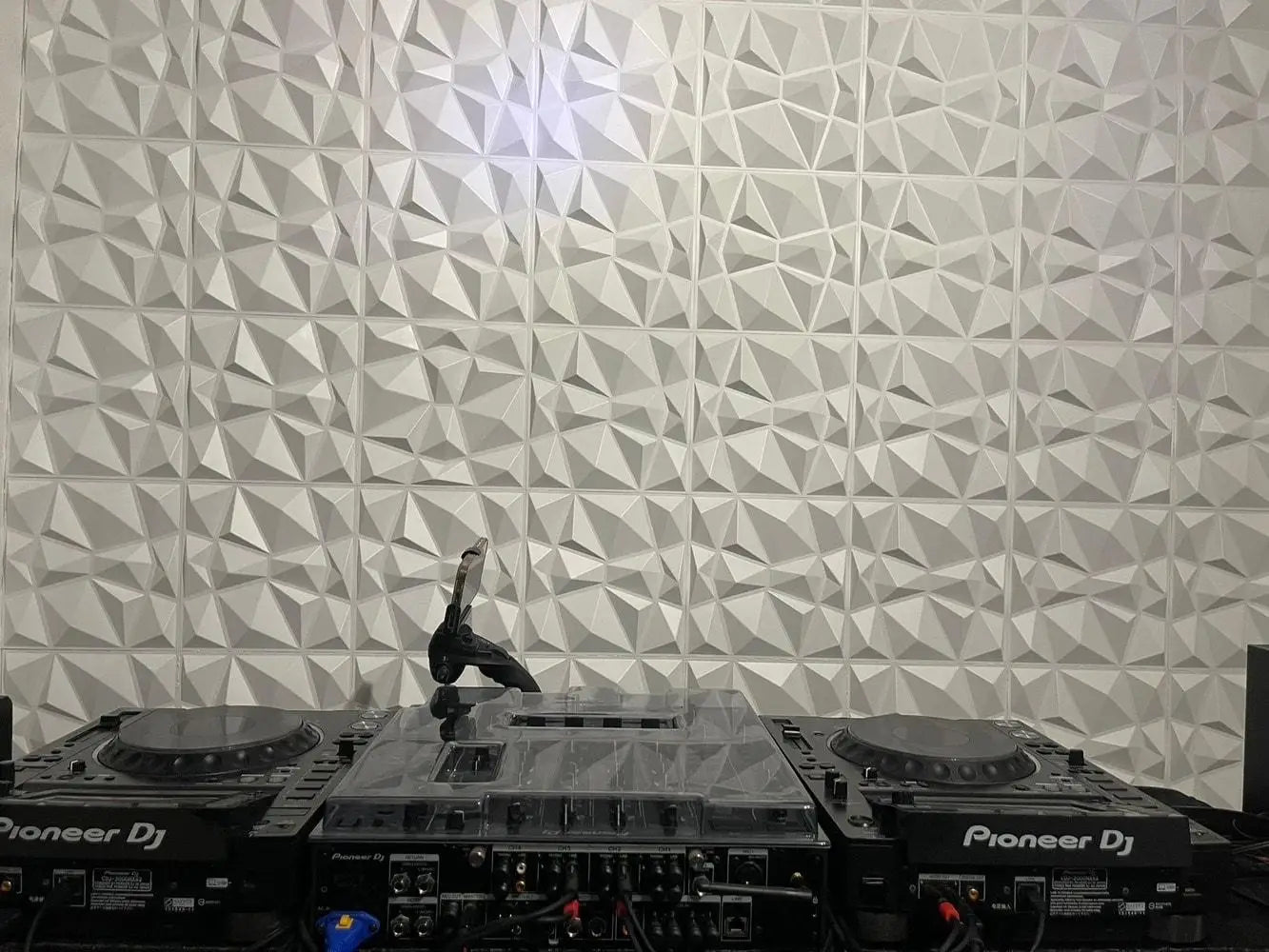 DJ equipment on a turntable with a geometric patterned wall in the background