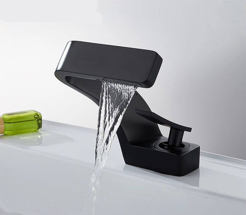 Black waterfall hot and cold water faucet with water flowing, TOLM brand visible.