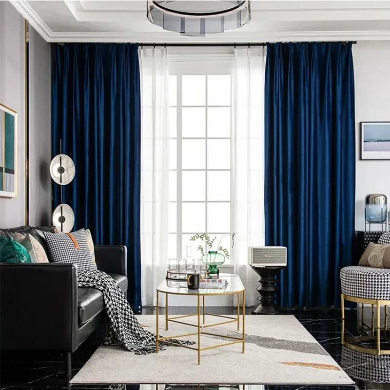 Modern living room with navy blue curtains, a black sofa, and a gold coffee table.