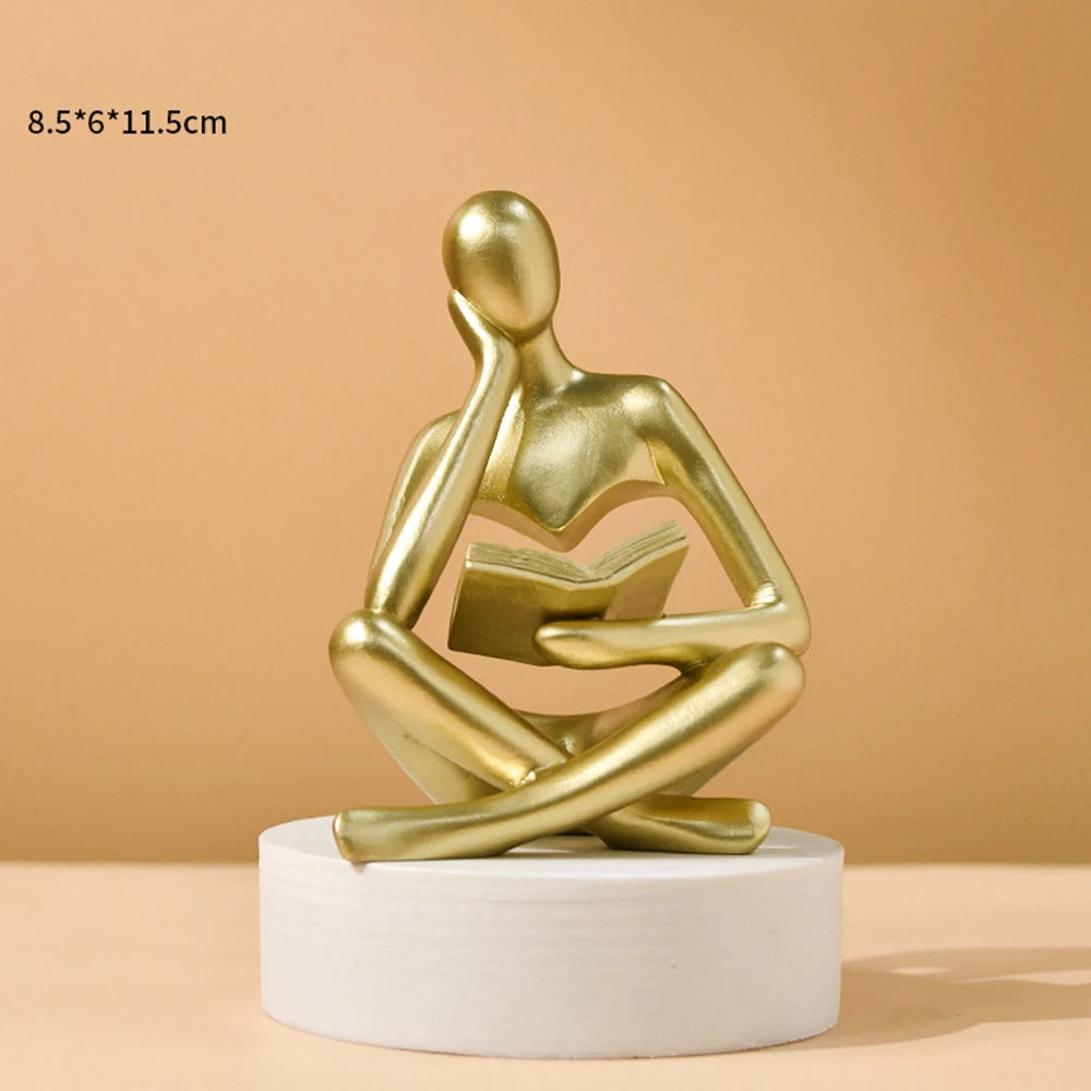 Gold abstract sculpture on a white base against a beige background