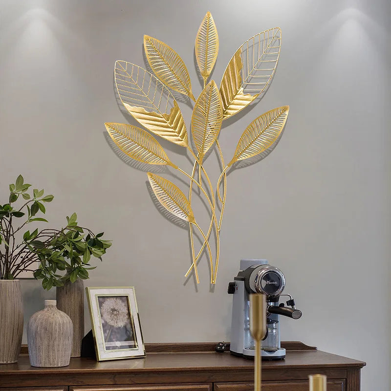 Gold leaf wall art on a neutral wall with decor items below.