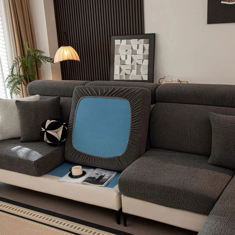 Gray sectional sofa with a blue cushion in a living room setting.