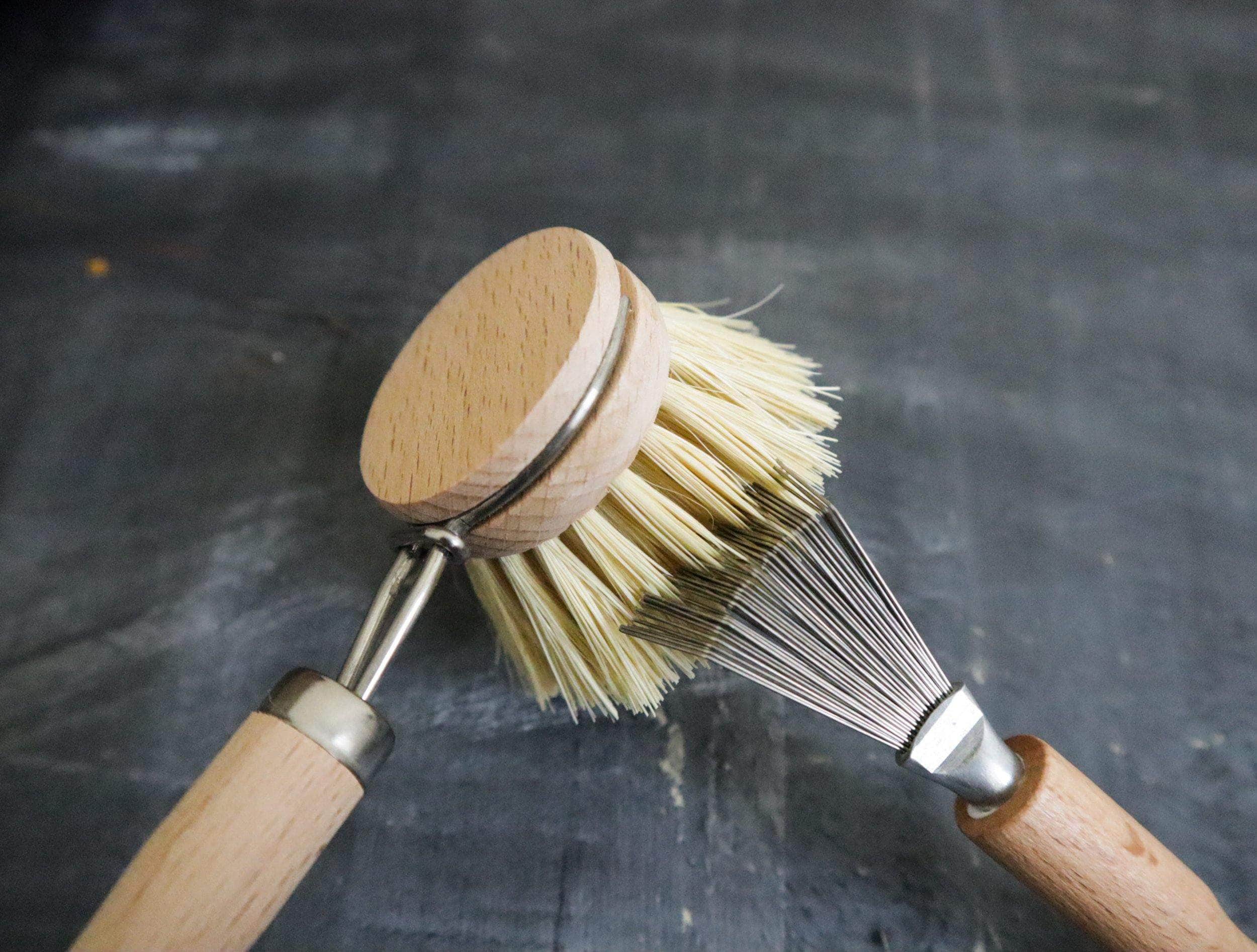 Two wooden-handled brushes with bristle heads on a dark background